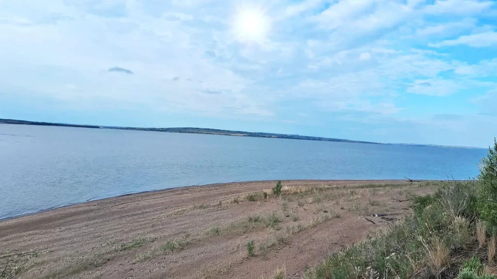 Scenic view of water from a hillside, showcasing the shimmering surface and surrounding greenery.